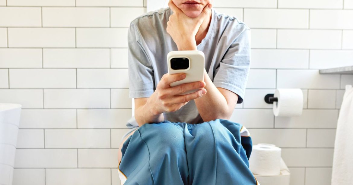 0_Woman-sitting-on-toilet-using-smartphone-in-modern-bathroom.jpg